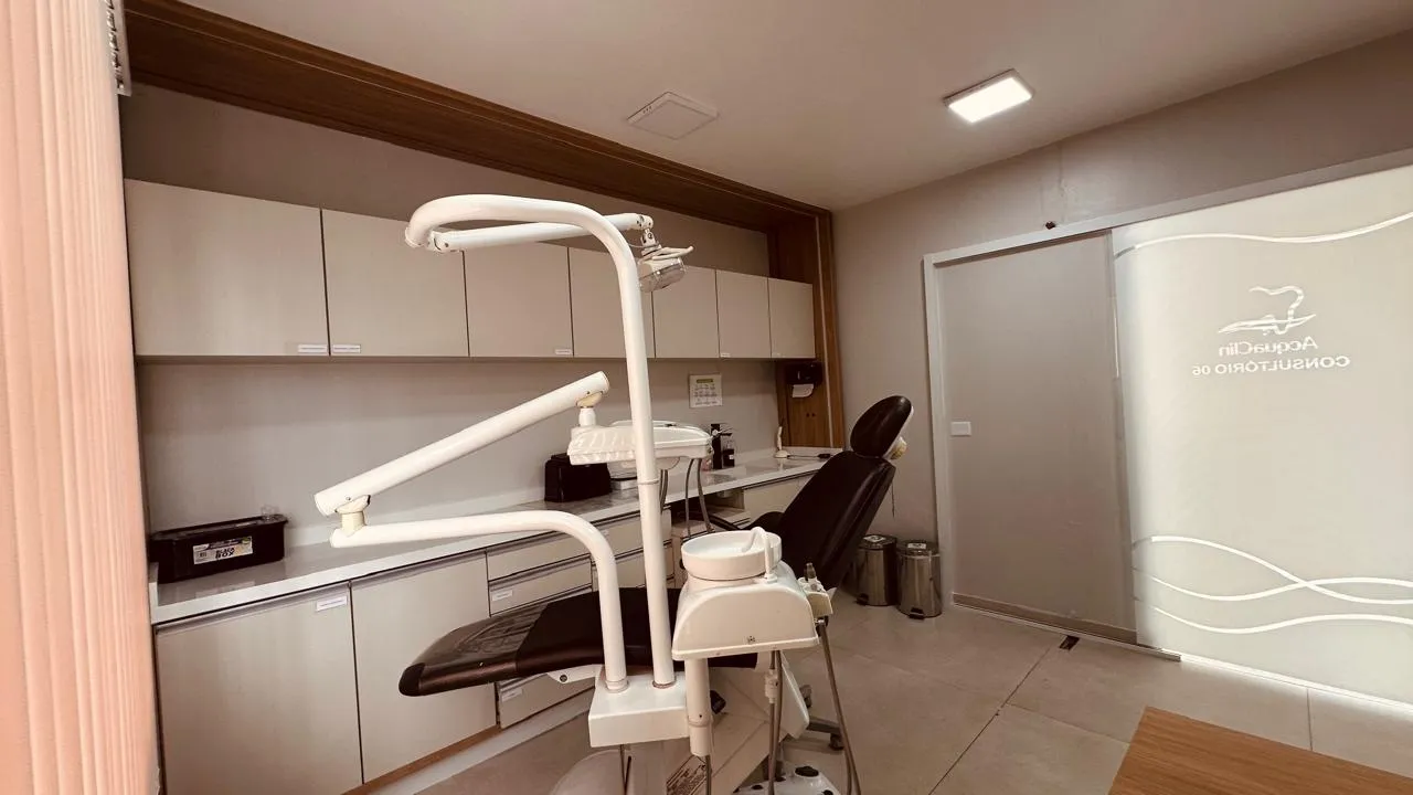 Consultório com cadeira odontológica, armários claros e marcenaria em madeira